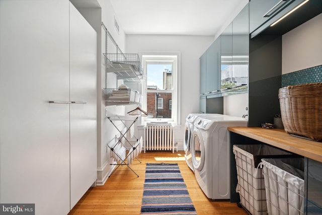 washroom featuring light hardwood / wood-style flooring, washer and dryer, and radiator