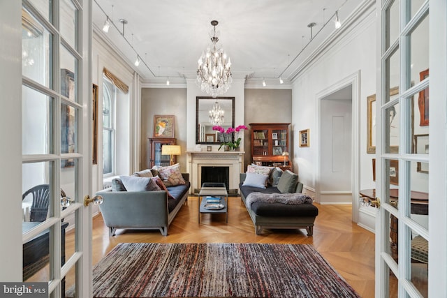 living area with rail lighting, a healthy amount of sunlight, a notable chandelier, and parquet floors