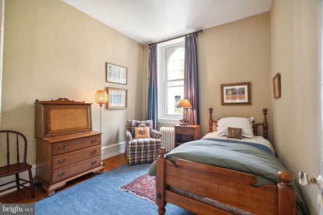 bedroom with radiator heating unit and dark hardwood / wood-style floors