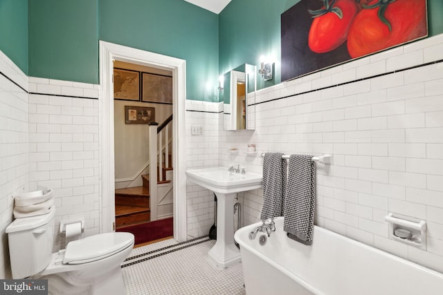 bathroom with tile walls, tile floors, toilet, and a bathtub