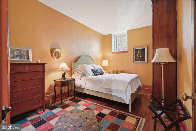 bedroom with vaulted ceiling, dark hardwood / wood-style flooring, and radiator