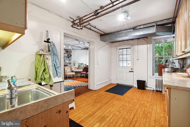 entrance foyer with light hardwood / wood-style floors, radiator heating unit, and sink