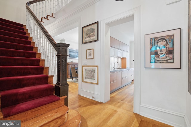 stairs with light hardwood / wood-style flooring and sink