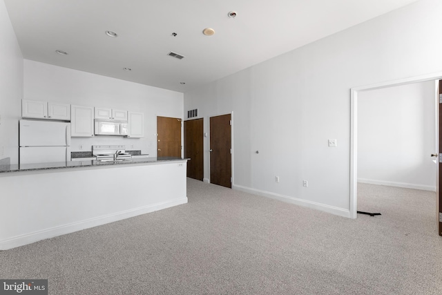 kitchen featuring white cabinets, light colored carpet, white appliances, and dark stone counters