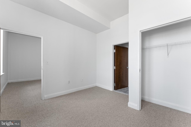 unfurnished bedroom featuring light carpet and a closet