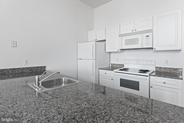 kitchen with dark stone countertops, white appliances, white cabinetry, and sink