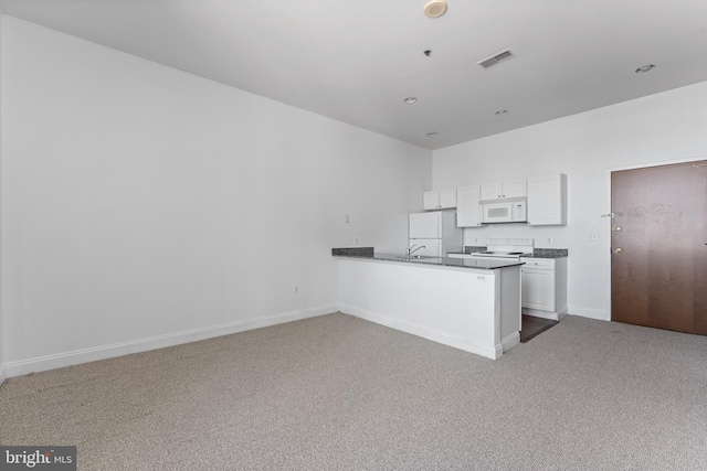 kitchen with carpet floors, kitchen peninsula, white appliances, white cabinets, and sink