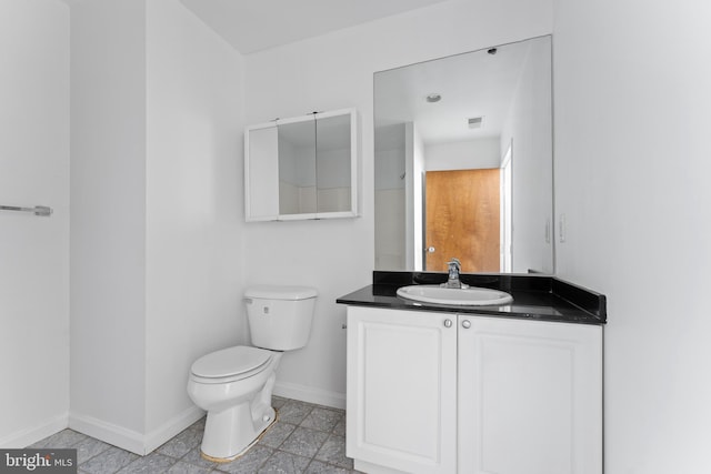 bathroom with tile flooring, toilet, and vanity with extensive cabinet space