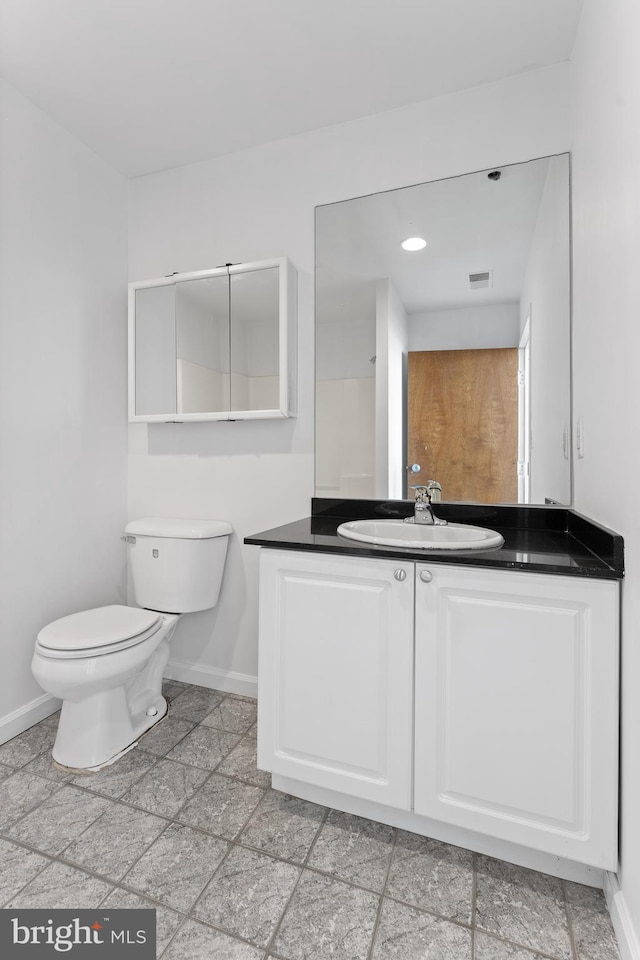 bathroom with toilet, vanity, and tile flooring