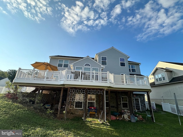 rear view of property with stone siding, a yard, a wooden deck, and fence