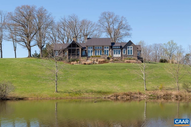 back of house featuring a lawn and a water view