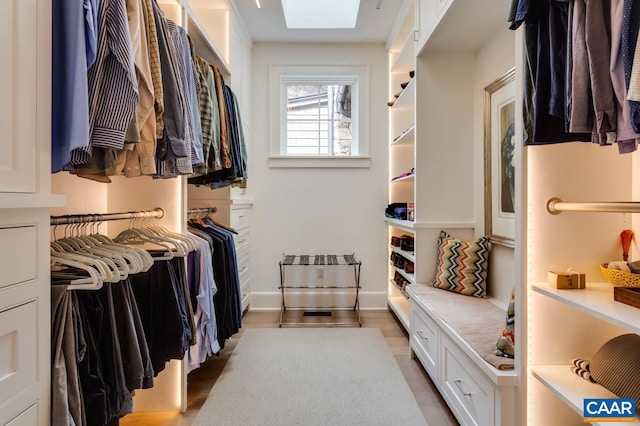 spacious closet with a skylight and light hardwood / wood-style flooring