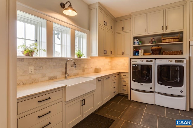 washroom with a wealth of natural light, dark tile flooring, washing machine and dryer, and sink