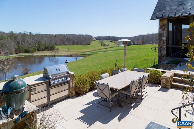 view of terrace featuring a water view, an outdoor kitchen, and grilling area