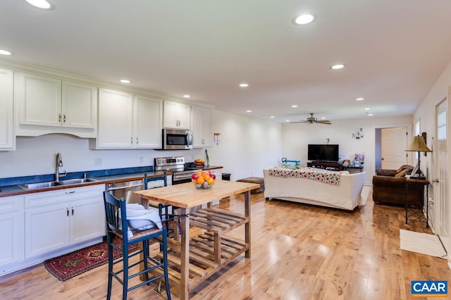 kitchen with light hardwood / wood-style flooring, ceiling fan, stainless steel appliances, white cabinetry, and sink