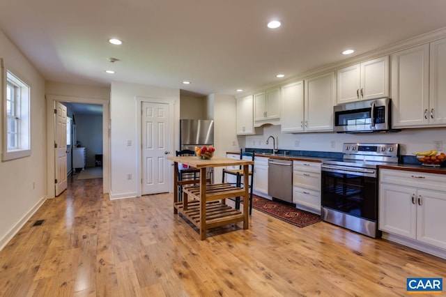 kitchen with light hardwood / wood-style flooring, stainless steel appliances, and white cabinetry