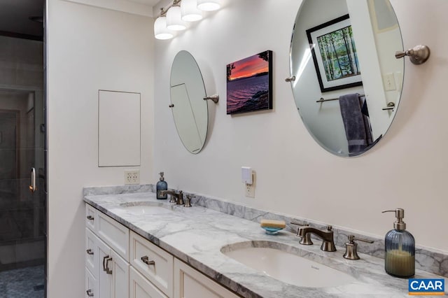 bathroom featuring large vanity, a shower with shower door, and double sink