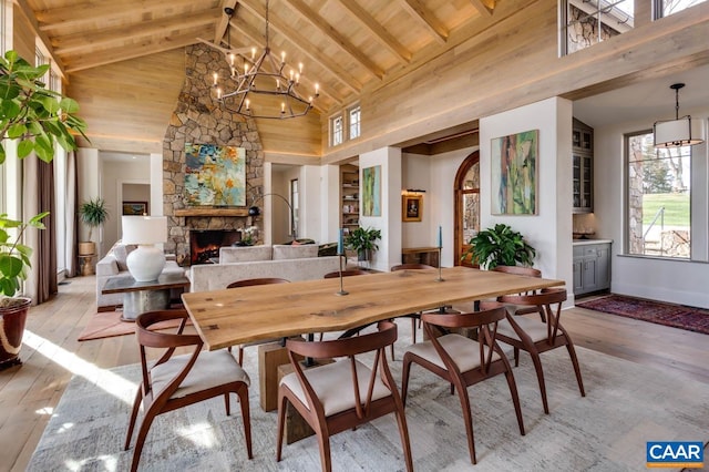 dining room with wooden ceiling, a fireplace, light wood-type flooring, and a chandelier