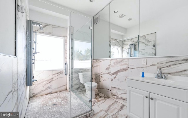 bathroom featuring tile floors, toilet, vanity with extensive cabinet space, tile walls, and walk in shower