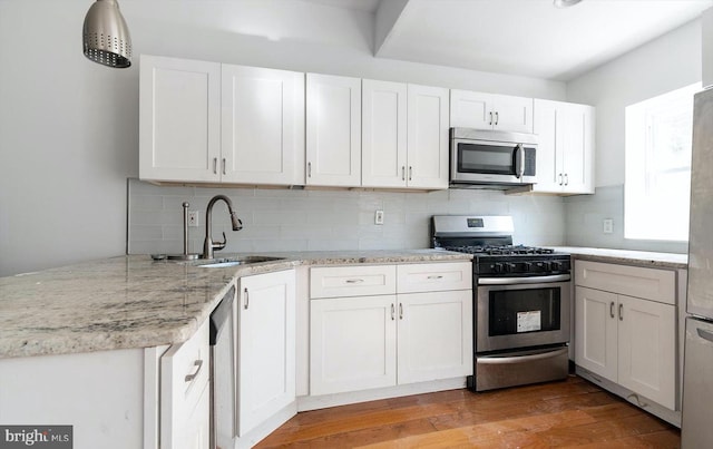 kitchen with backsplash, white cabinetry, hardwood / wood-style floors, and appliances with stainless steel finishes