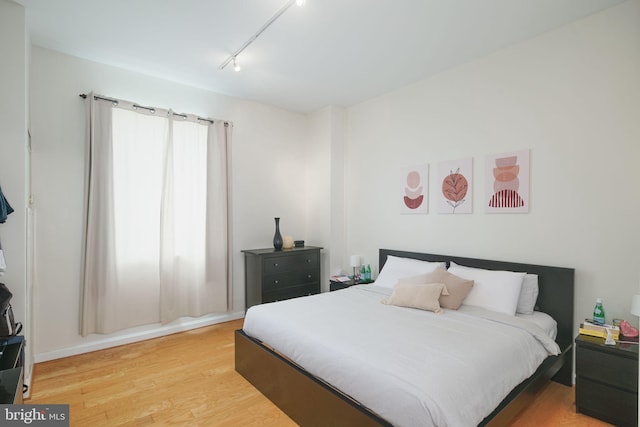 bedroom featuring rail lighting and light hardwood / wood-style flooring