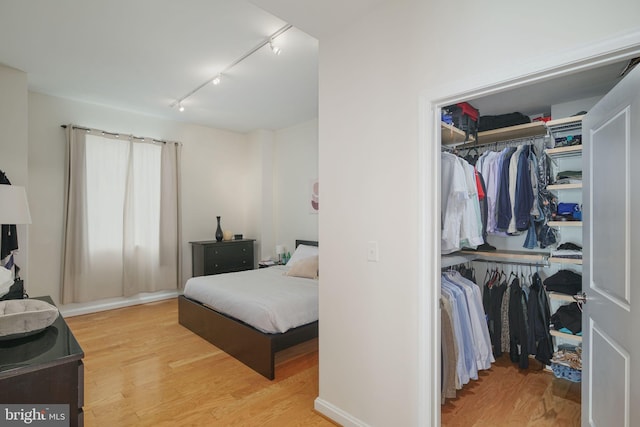 bedroom featuring a closet, rail lighting, and light hardwood / wood-style flooring