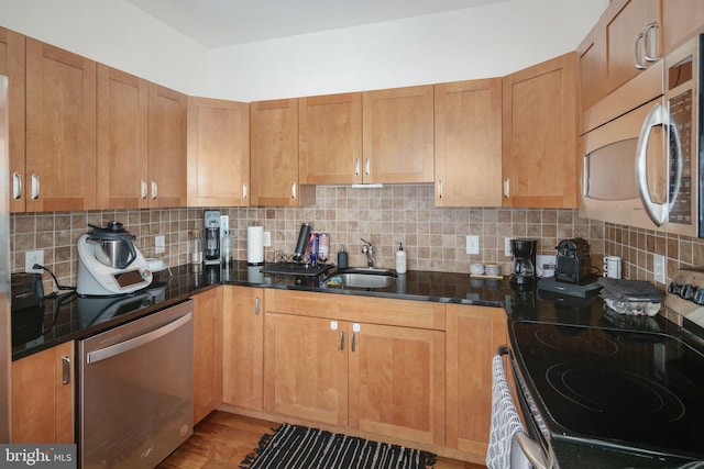 kitchen featuring backsplash, sink, dark stone counters, and appliances with stainless steel finishes