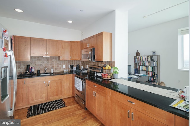 kitchen featuring tasteful backsplash, sink, stainless steel appliances, and light hardwood / wood-style floors