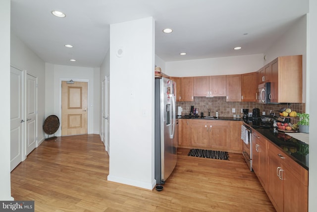 kitchen featuring sink, light wood-type flooring, stainless steel appliances, and backsplash