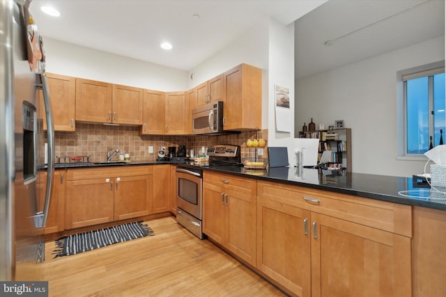 kitchen with sink, light hardwood / wood-style flooring, tasteful backsplash, kitchen peninsula, and stainless steel appliances