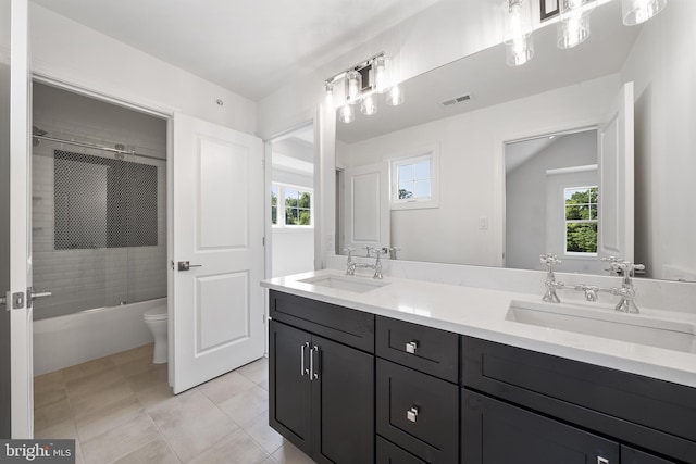 full bathroom featuring tiled shower / bath combo, dual bowl vanity, toilet, and tile floors