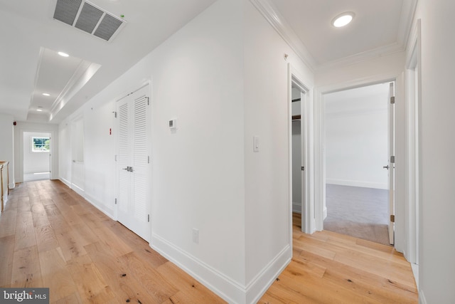 hall featuring a raised ceiling, ornamental molding, and light hardwood / wood-style floors