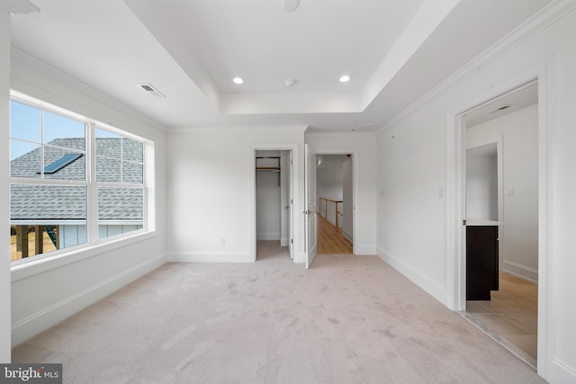 unfurnished bedroom with light carpet, crown molding, and a raised ceiling