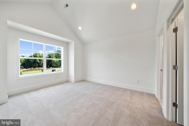 carpeted spare room with vaulted ceiling