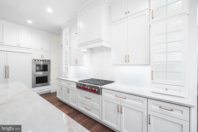 kitchen with dark hardwood / wood-style floors, stainless steel appliances, white cabinetry, and light stone countertops