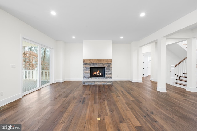 unfurnished living room with a stone fireplace and dark hardwood / wood-style floors