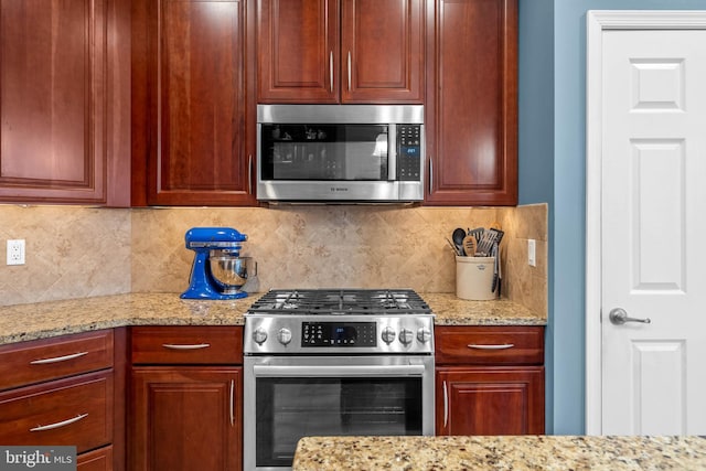 kitchen featuring backsplash, light stone counters, and stainless steel appliances