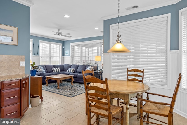 tiled dining area featuring ceiling fan and ornamental molding