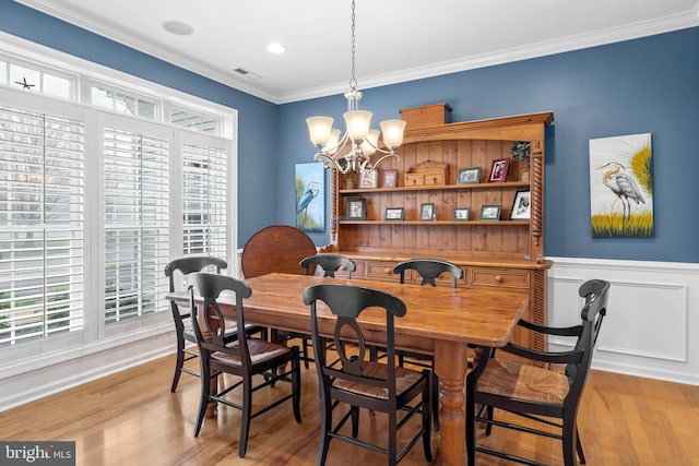 dining space with a chandelier, ornamental molding, and light hardwood / wood-style floors