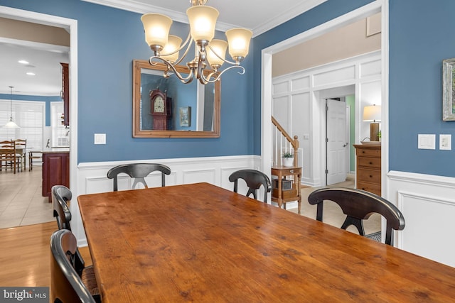 dining area with a notable chandelier, crown molding, and light wood-type flooring