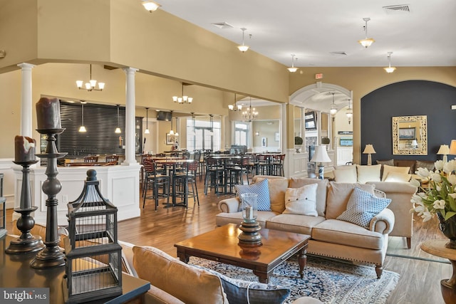 living room with decorative columns, a notable chandelier, and light wood-type flooring