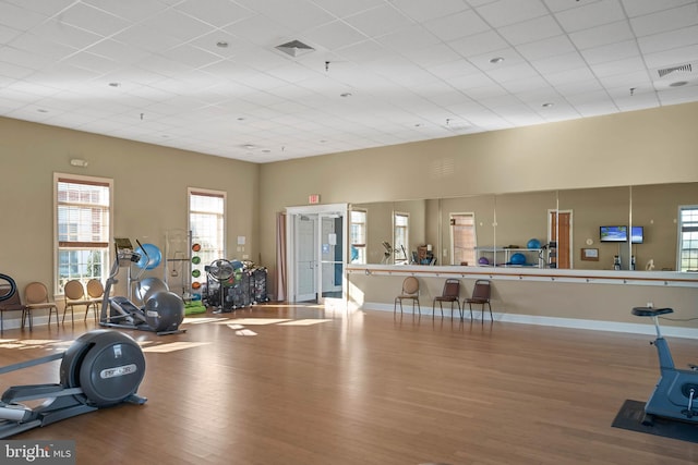 gym featuring a high ceiling, wood-type flooring, and a paneled ceiling