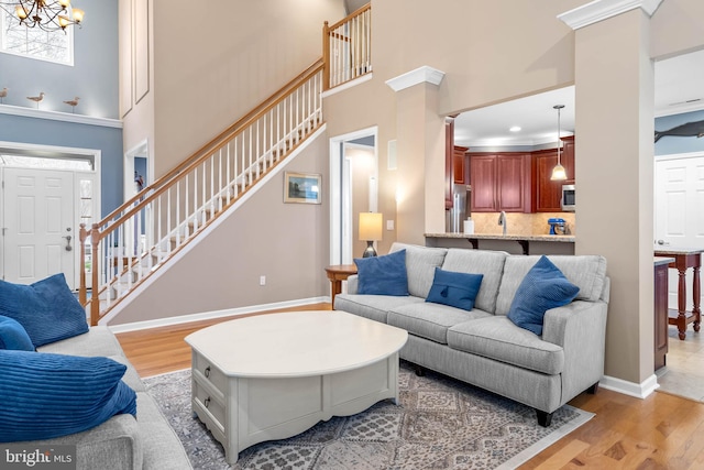 living room with a high ceiling, light hardwood / wood-style floors, and a notable chandelier