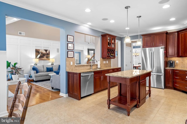 kitchen featuring sink, a kitchen island, appliances with stainless steel finishes, light hardwood / wood-style floors, and light stone countertops