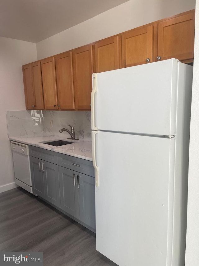 kitchen with gray cabinets, white appliances, dark hardwood / wood-style flooring, backsplash, and sink