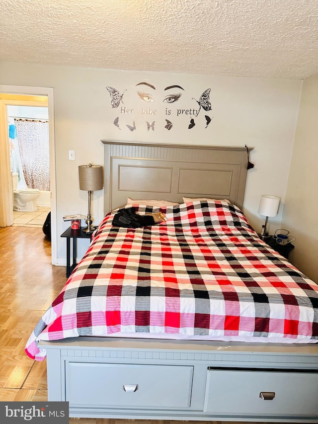 unfurnished bedroom featuring a textured ceiling, connected bathroom, and light parquet flooring