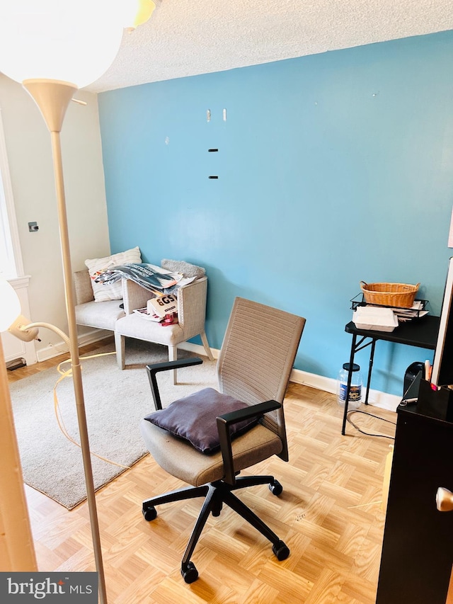 office area with light parquet floors and a textured ceiling