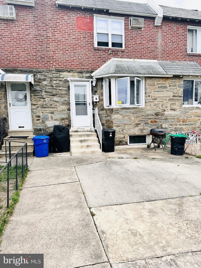 back of property with a patio area and a wall unit AC