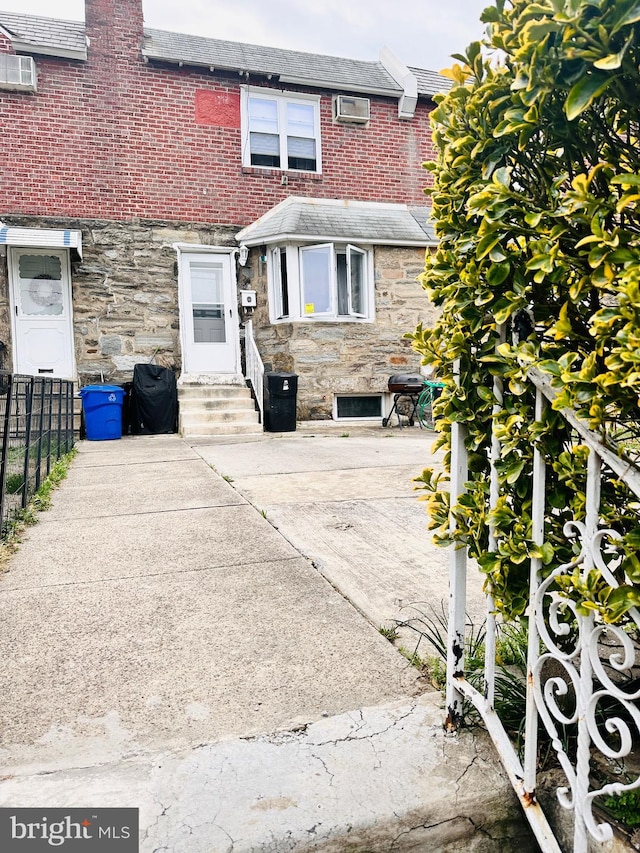 view of front of home with an AC wall unit and a patio