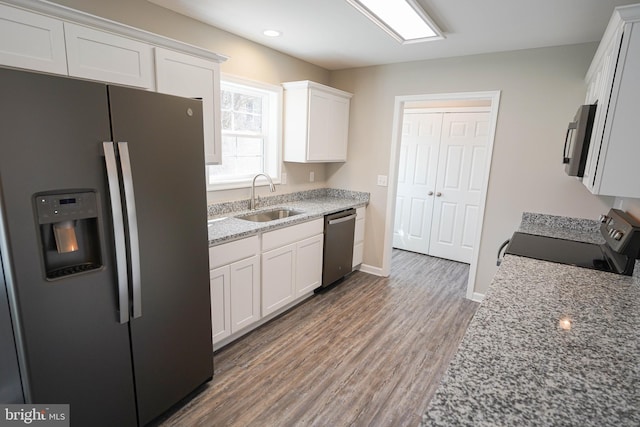 kitchen featuring appliances with stainless steel finishes, sink, light stone countertops, white cabinets, and dark hardwood / wood-style flooring